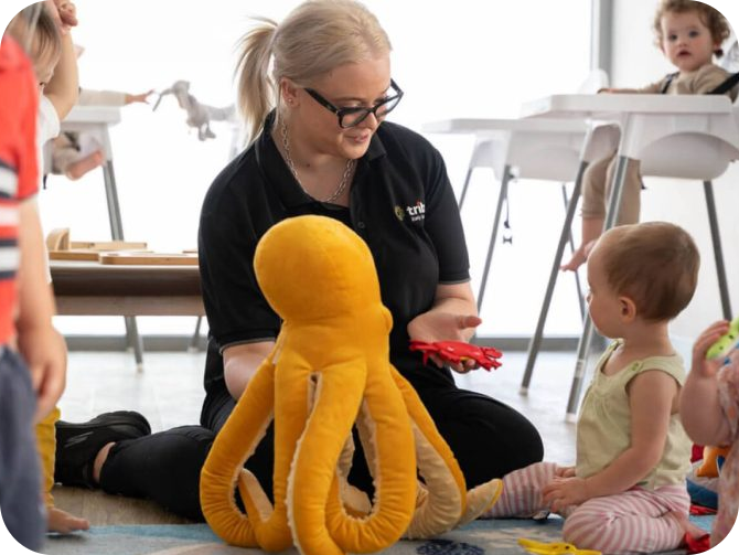 Educator sitting with a child playing with a toy